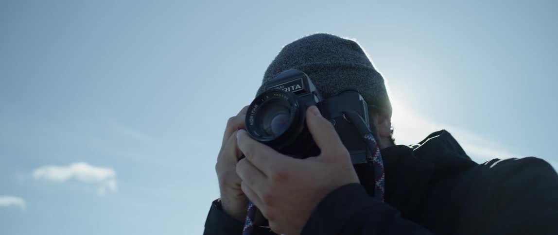 A man taking a photo outside adjusts the focus on his camera