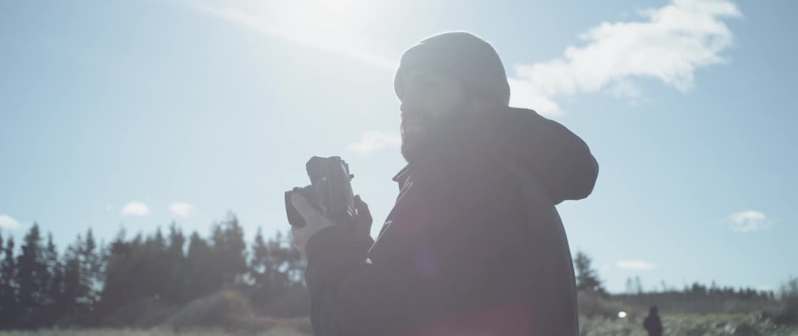 A man holds a camera outside and photographs nature