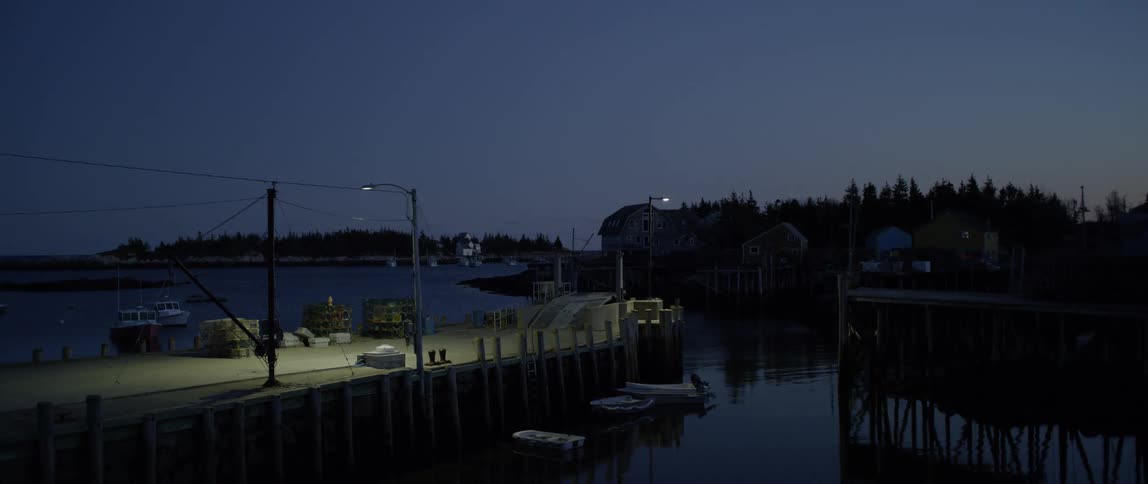 Dusk is settling over a harbor in a small town