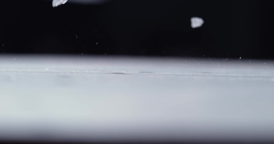 White crystals fall and bounce on a surface