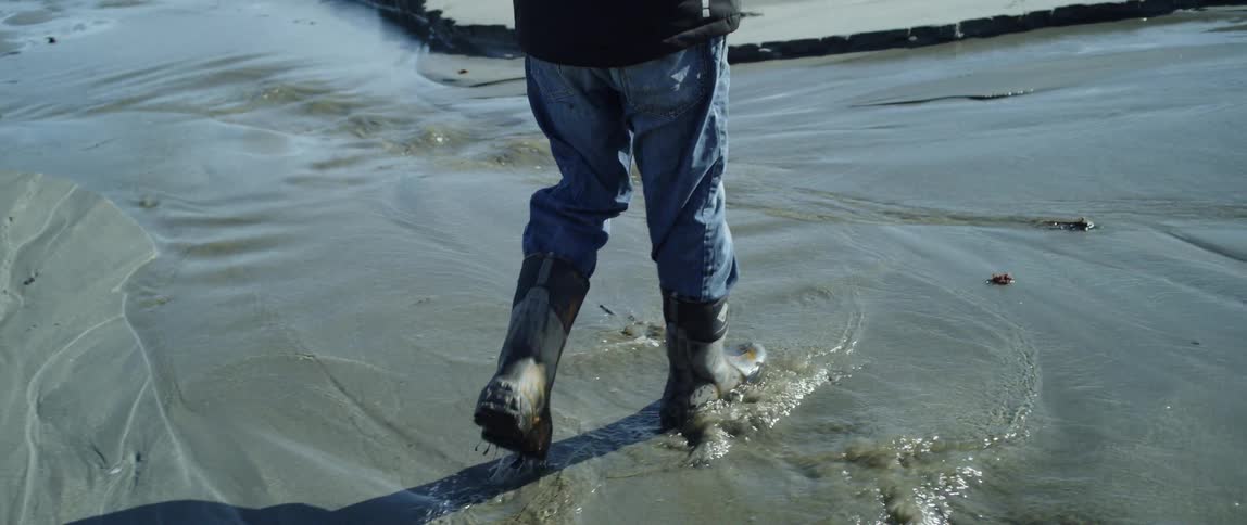 A man walks through flowing water in boots