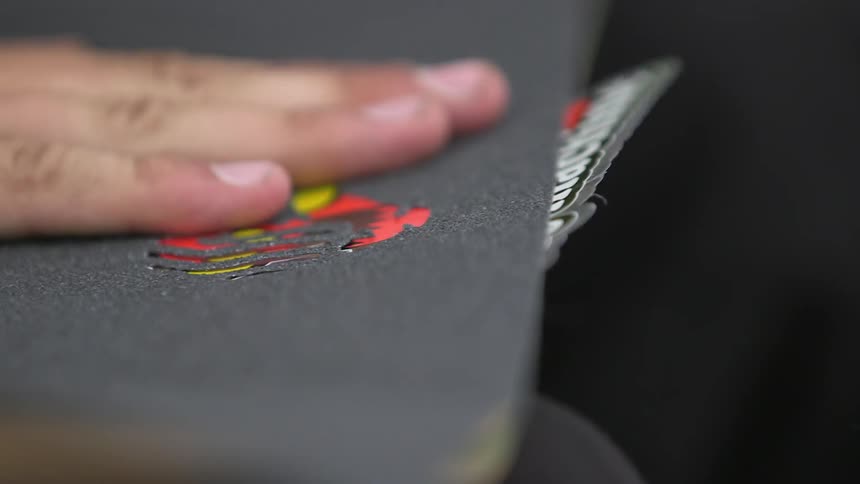 Man applying a cover to his skateboard and patting it down