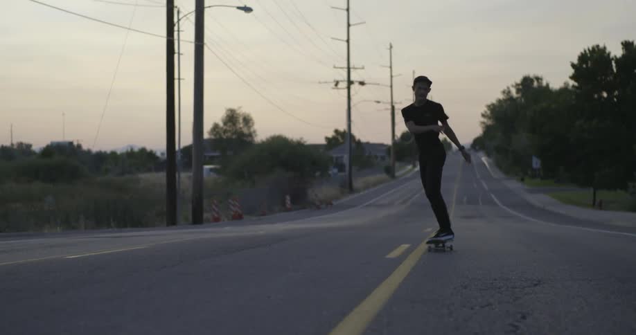 Man does a jump on his skateboard while moving down a road