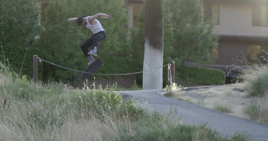 A man jumps over a rope fence while skateboarding