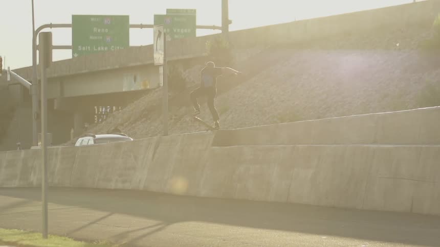 Boy riding a skateboard near an overpass