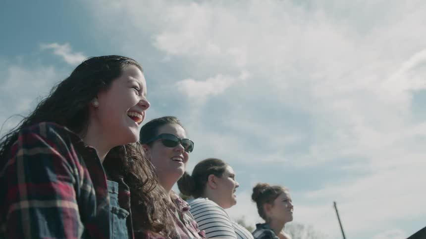Four woman sit outside smiling and laughing