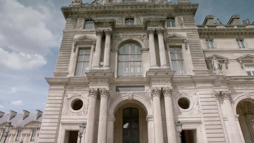 People walk up the steps of a building as others walk past