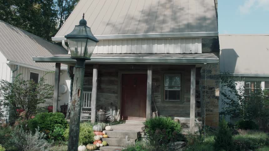 Pumpkins sit on the steps of a small house