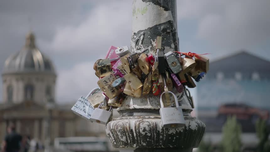 An assortment of locks are wrapped around a lamp post in the city