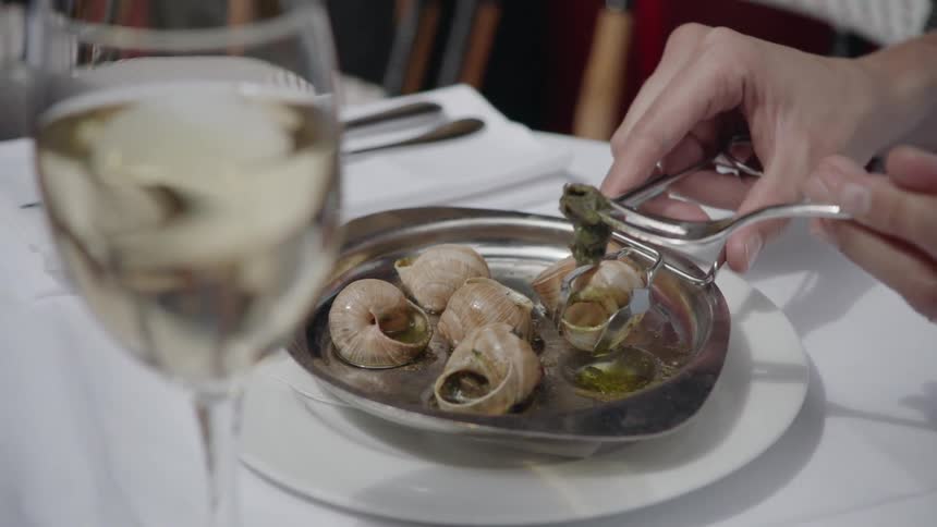 A person eats escargot in a restaurant