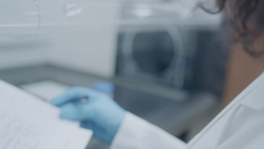 A woman is examining paperwork as she is working in a lab