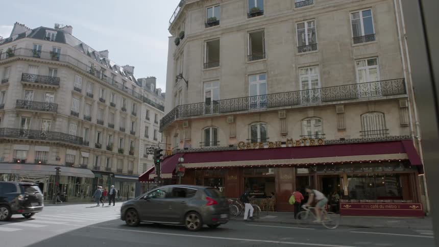 People walk and bike across a city intersection as cars drive by