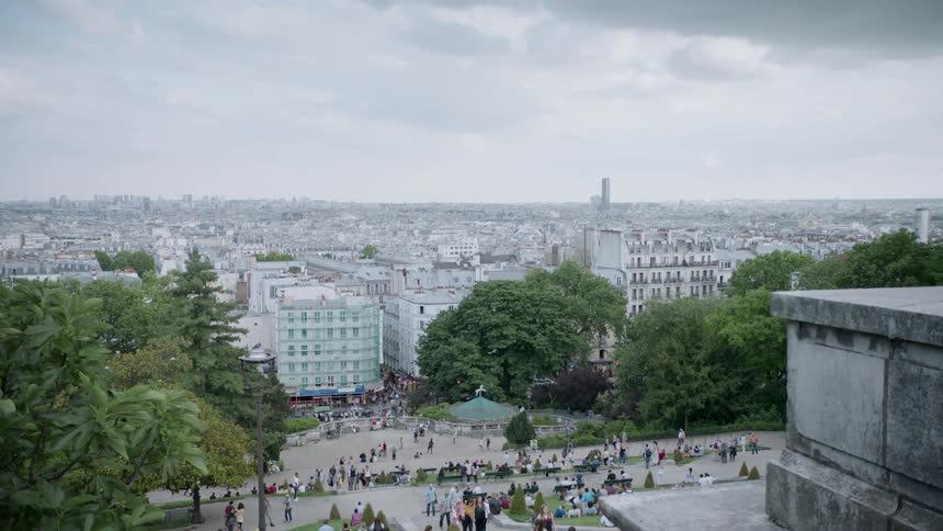 People walk and sit in a park overlooking the city