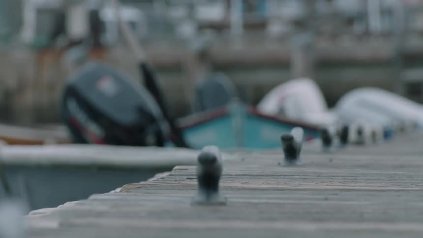 Dinghies are bobbing in the water while tied up to a pier during the day