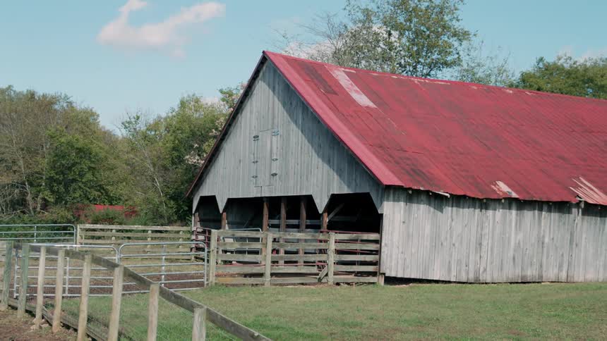 Barn with a red roof with a fenced in area of yard