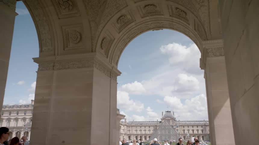 Tourists walk around the square in front of the louvre museum