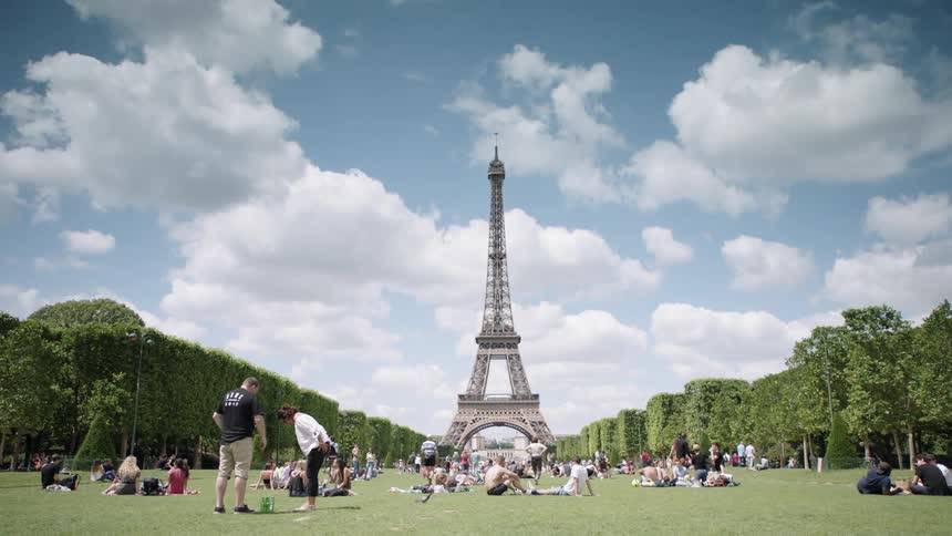 People sit on the grass in the park near the eiffel tower