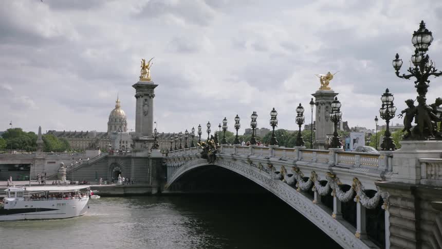 Boat floating down a river and a large bridge overhead