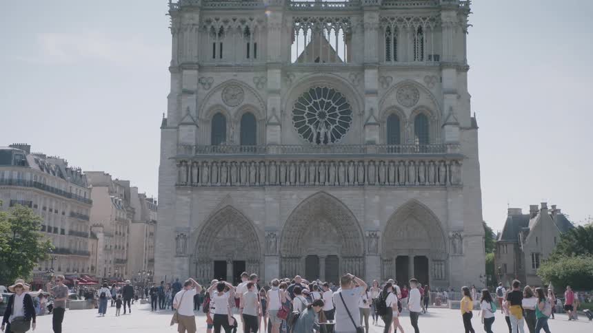 Large crowd of people walk in a city square on a sunny day