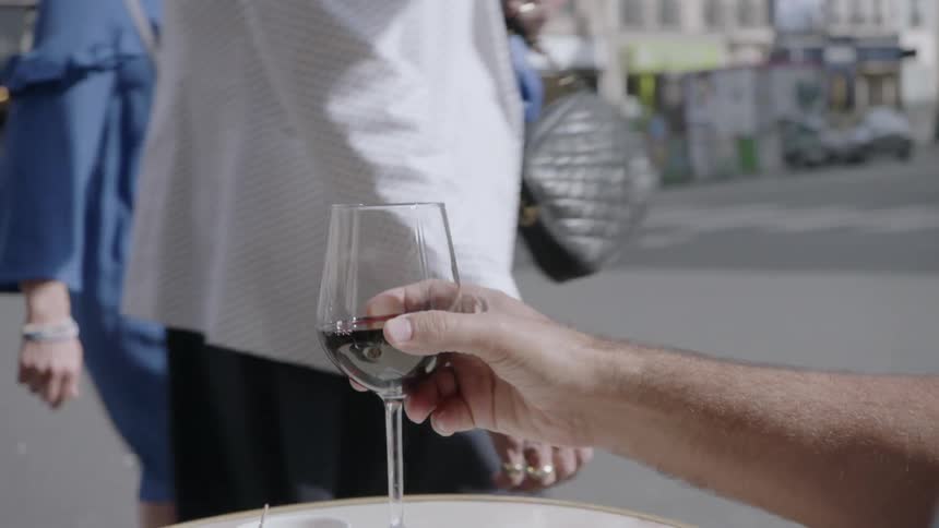 Man drinks wine outside at a table on a sunny day
