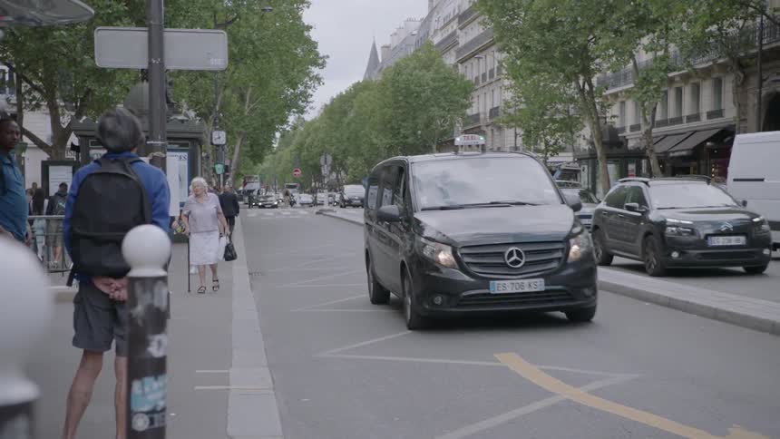 People walk on a sidewalk next to a traffic clogged street