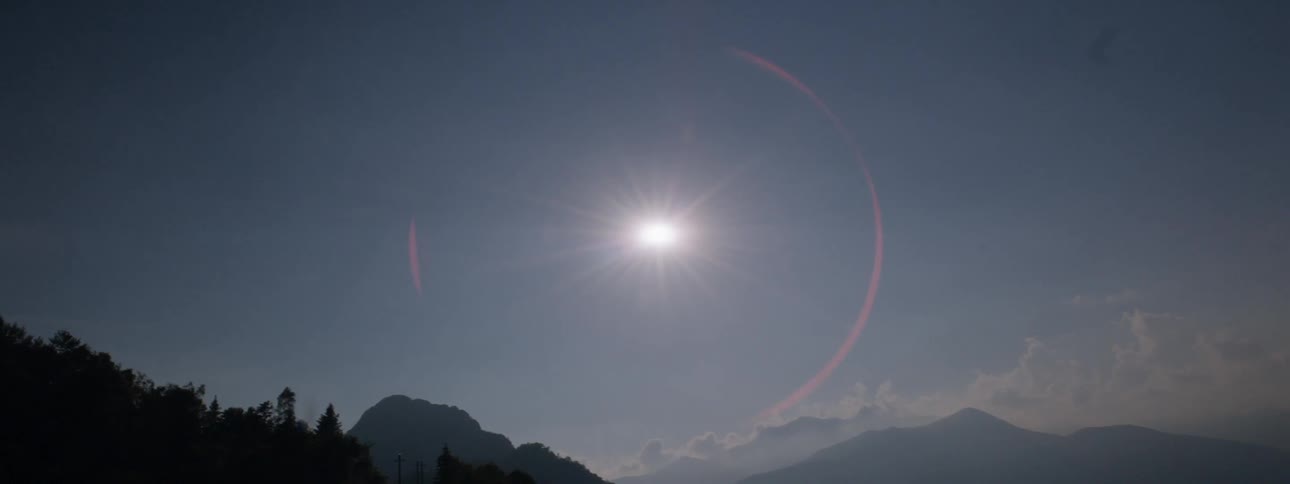 The sun shines above mountains