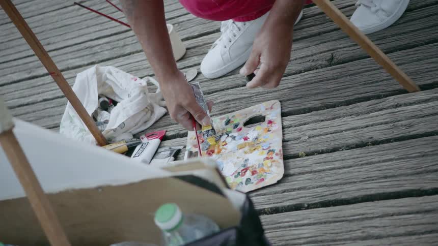 Artist applying paint from a tube to their palette