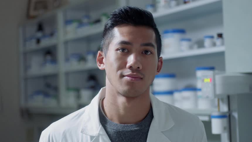 A man in a lab coat looks up from his work