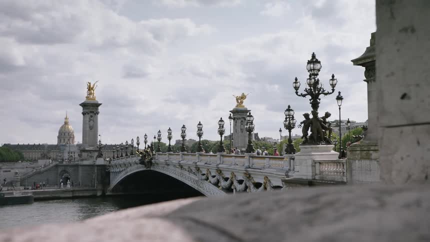 People are walking across a bridge in an old world city on a cloudy day