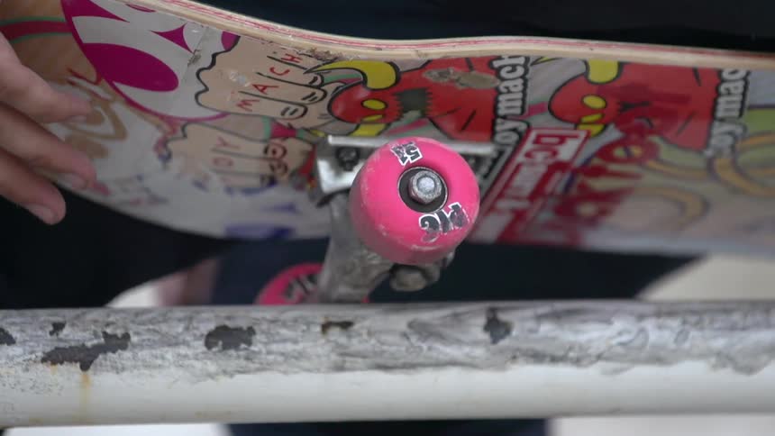 A white male scratches at his skateboard outside