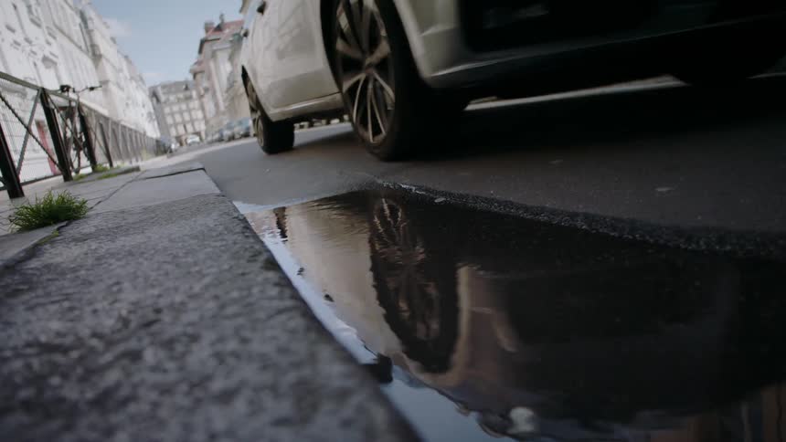 A car drives by a puddle on a street
