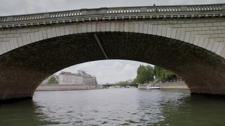 People walk across a bridge as a boat travels under it