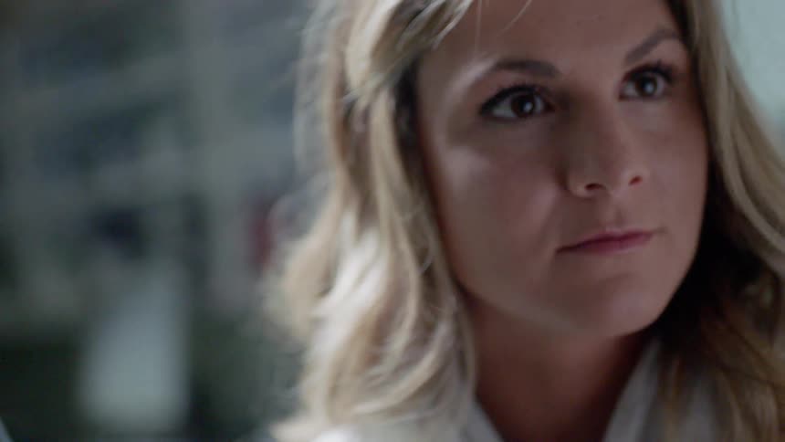 A woman in a workplace looks up from what she's doing