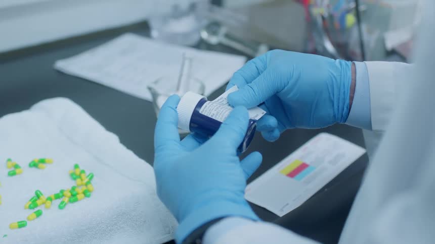 A pharmacist puts a label on a prescription bottle