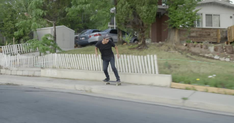 Man riding a skateboard doing a sidewalk then jumps into the street