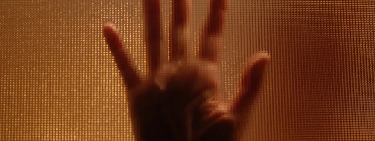 A hand is pressed against glass