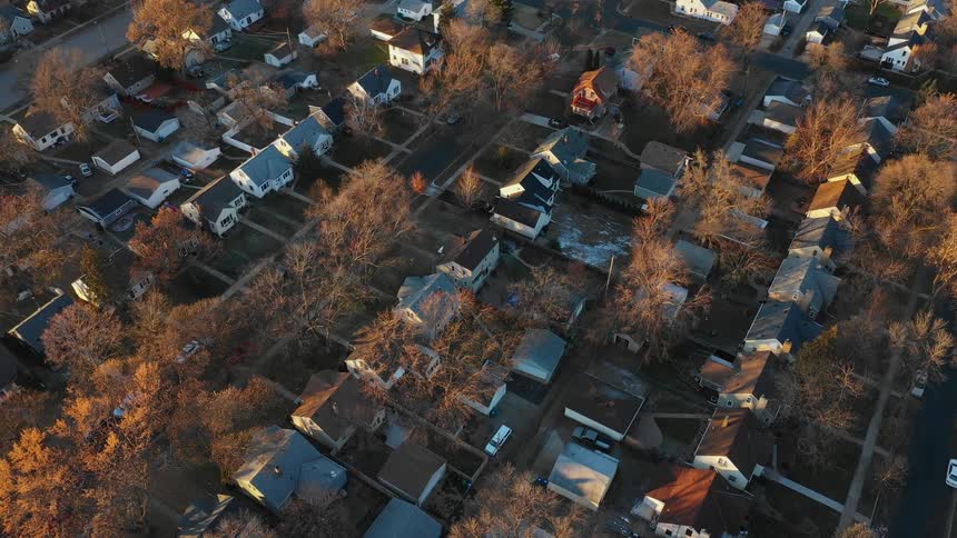 Fall colors are showing on trees in a neighborhood at dawn