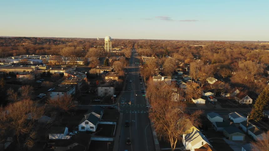 Cars driving down a road in a small town on a bright day