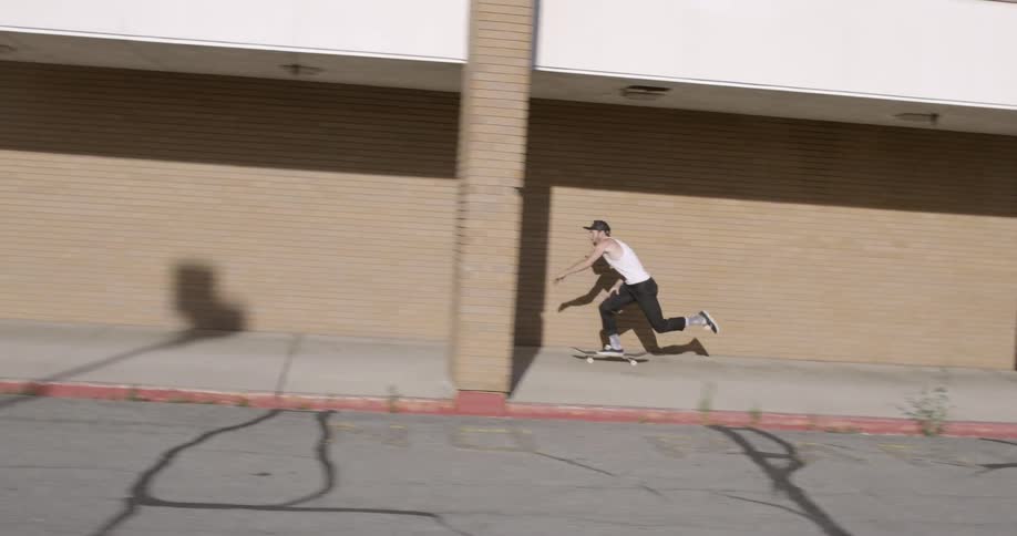 Man jumps on skateboard and rides in front of building