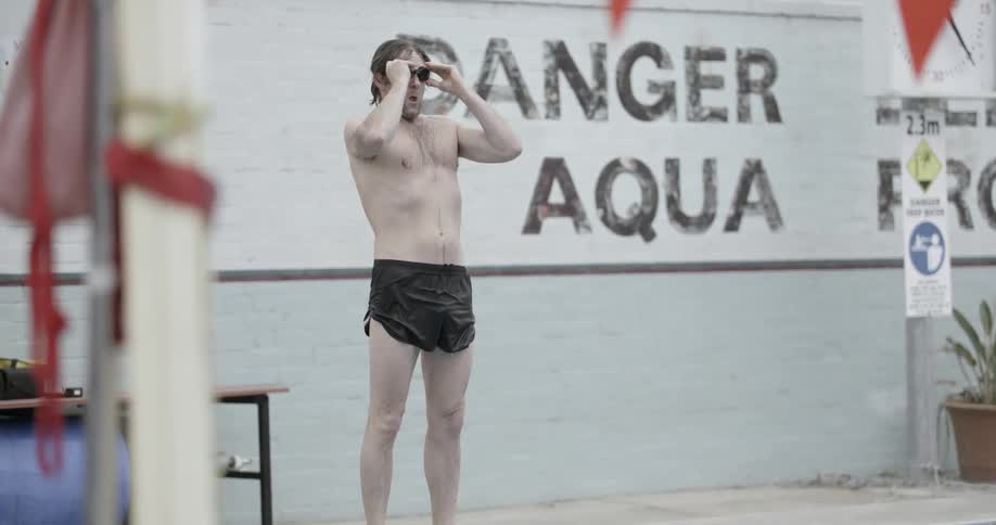 Man puts goggles on and dives into a swimming pool outside