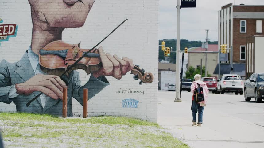 A large mural on the side of a building next to a very busy city street