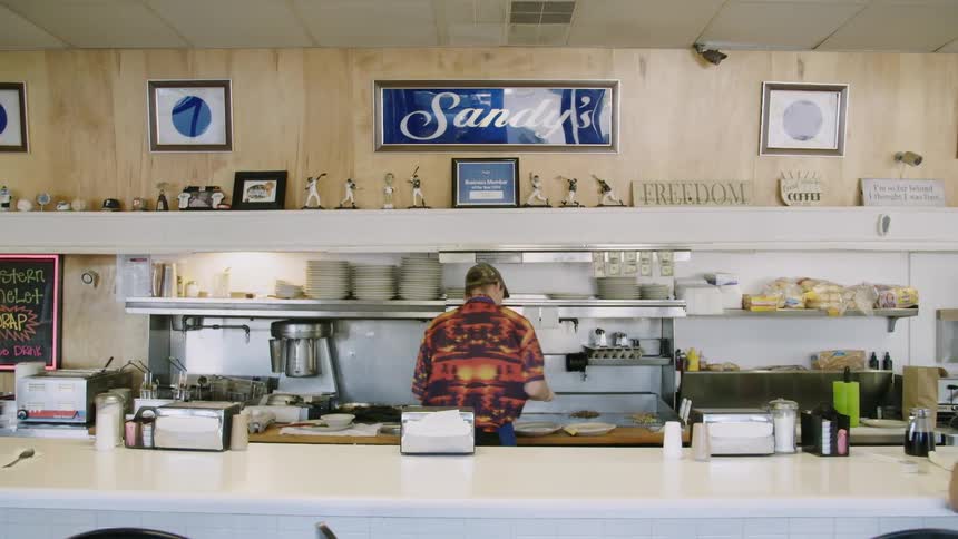 A person is plating food in a diner during the day