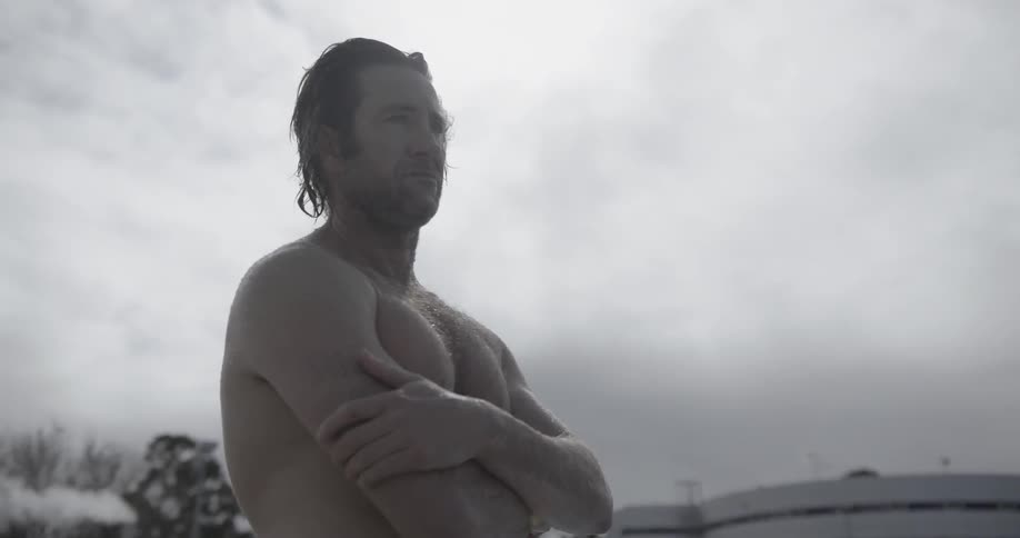 A man is standing outside with his arms crossed looking around