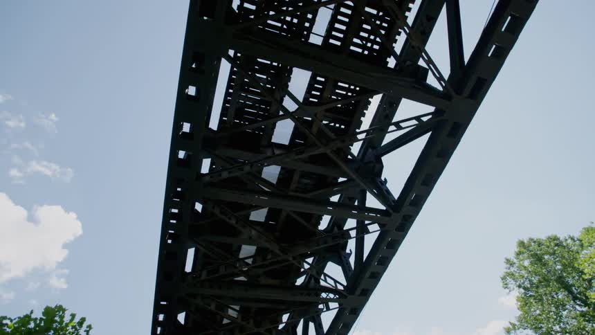 The sun is shining through the train tracks on the bridge