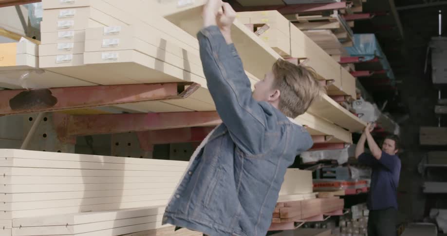 Workers carry a piece of lumber in a warehouse