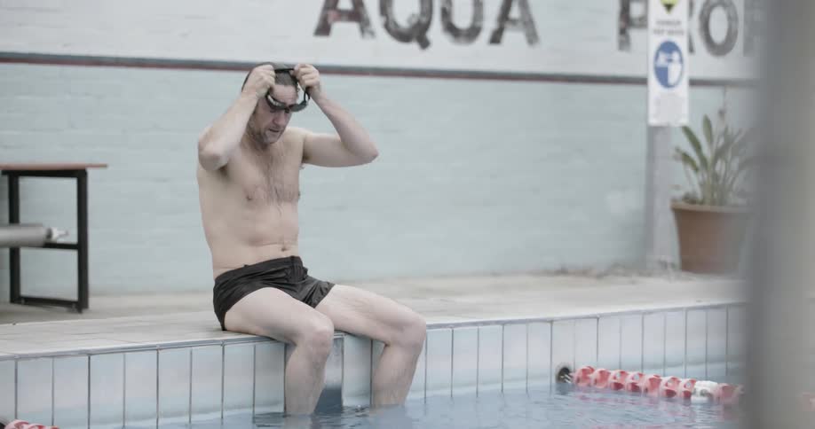 A man puts on goggles and jumps into a pool