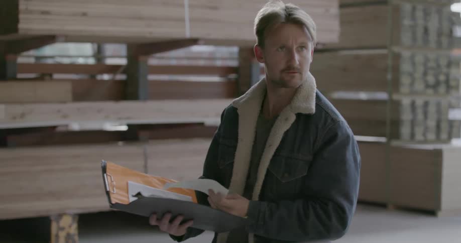 A man with a binder full of papers is walking around a checking items