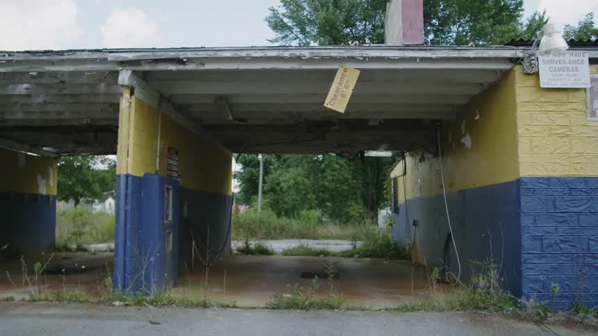 Weeds grow around an abandoned car wash