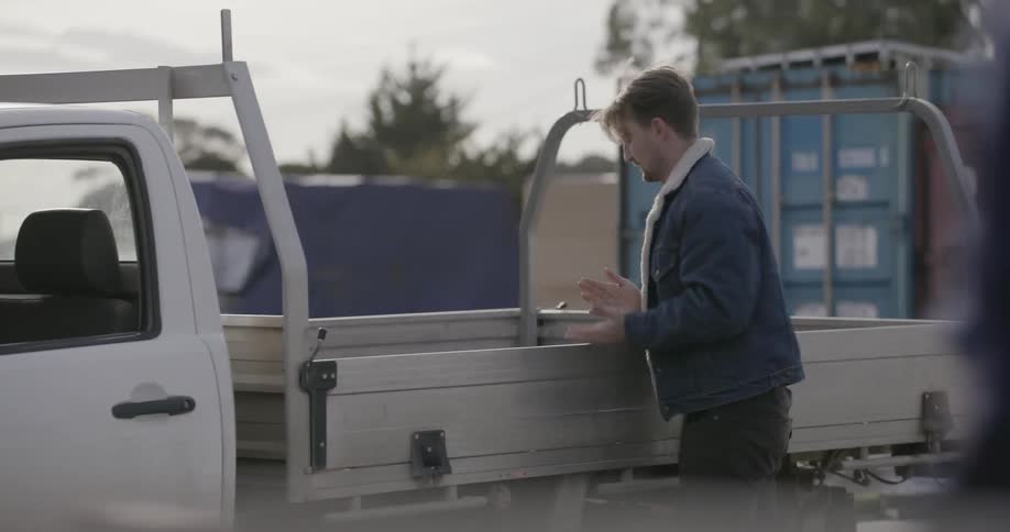 A man is putting lumber in the back of a truck