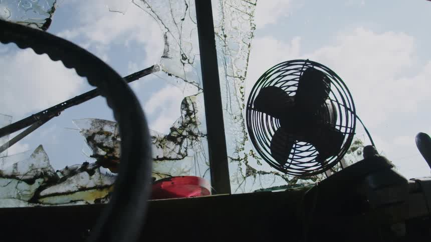 A fan is sitting on a dashboard of a broken down semi truck